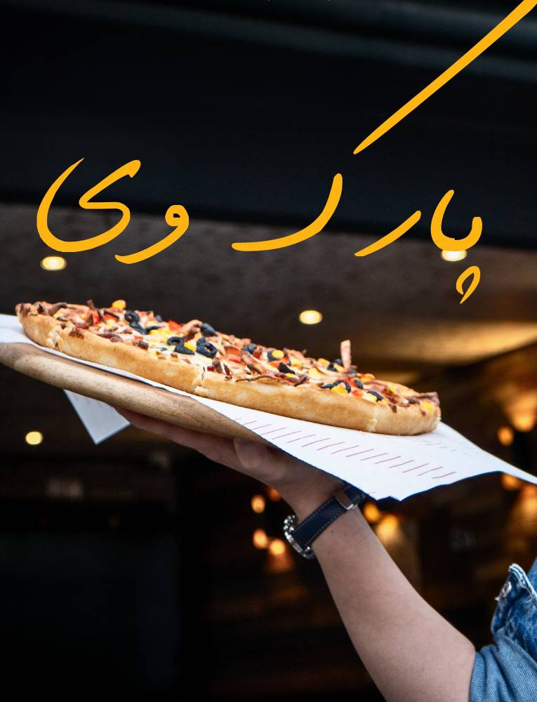 Park Way server holding a fresh thin-crust pizza topped with olives and corn in Chorlton. 